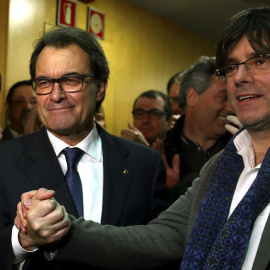 El presidente catalán en funciones, Artur Mas (i), estrecha la mano del alcalde de Girona, Carles Puigdemont (d), a su llegada a la sede de CDC tras la rueda de prensa que ha ofrecido hoy en el Palau de la Generalitat en la que ha anunciado