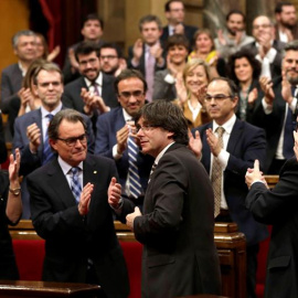 El nuevo presidente de la Generalitat, Carles Puigdemont (c), tras ser elegido durante el pleno de investidura celebrado esta tarde en el Parlament de cataluña. EFE/Alberto Estévez