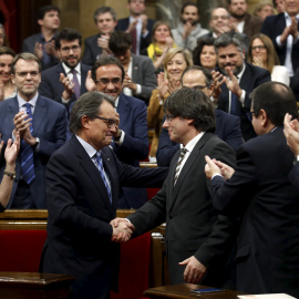 Artur Mas saluda al nuevo president de le Generalitat, Carles Puigdemont al término del pleno de investidura en el Parlament. - REUTERS