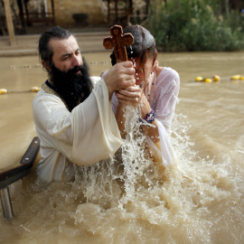 Un padre bautiza a su hijo en el Río Jordán. REUTERS/Nir Elias