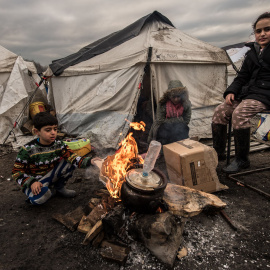 Varios inmigrantes intentan entrar en calor con un brasero en el campamento cerca de Dunkerque, donde viven alrededor de 2.500 de refugiados./AFP