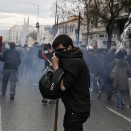A protester covers his face to avoid breathing tear gas during clashes marking a 24-hour general strike against planned pension reforms in Athens, Greece, February 4, 2016. REUTERS/Alkis Konstantinidis