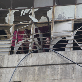 Una joven se asoma por la ventana de un edificio dañado por un bombardeo en Alepo. - REUTERS