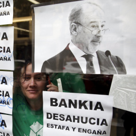 Una activista mira a través de una ventana desde el interior de la sucursal de Bankia en Madrid donde se ha llevado a cabo una protesta contra los desahucios. REUTERS/Andrea Comas