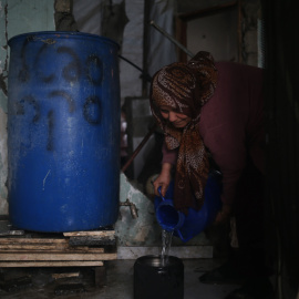 Etadal Abu Oda, una mujer palestina de 57 años de edad, toma agua de un tanque para limpiar los platos en su casa en Beit Hanoun, en el norte de la Franja de Gaza. Mohammed ABED / AFP