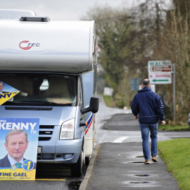 Un hombre camina junto a una autocaravana que muestra carteles del líder del partido Fine Gael (FG), el primer ministro irlandés Enda Kenny, en Castlebar en Irlanda. EFE/Aidan Crawley