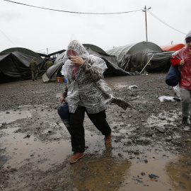 Varias personas tratan de protegerse de la lluvia en una de las tiendas del campamento de Slavonski Brod. - REUTERS