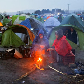 Varios refugiados se calientan junto al fuego entre sus tiendas de campaña en un campamento de refugiados en la frontera entre Grecia y Macedonia.- Valdrin Xhemaj (EFE)