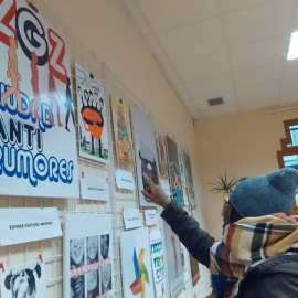 Dos jóvenes observan las propuestas para la portada del manual antirumores que se exponen en la Casa de las Culturas de Zaragoza.