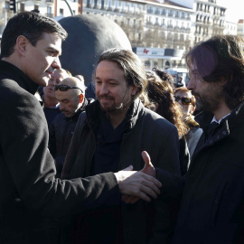 El secretario general del PSOE, Pedro Sánchez (i), saluda al responsable de Relaciones con la Sociedad Civil de Podemos, Rafael Mayoral, en presencia del líder de la formación, Pablo Iglesias, durante el homenaje.- EFE