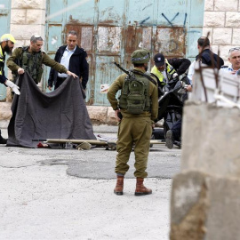 Soldados israelíes cubren el cuerpo sin vida de un palestino en Hebrón (Palestina) hoy, 24 de marzo de 2016.- EFE/Abed Al Hashlamoun