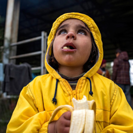 Una niña come un plátano en el campo de refugiados en Idomeni. EFE/ Georgi Licovski