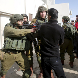 Un soldado israelí apunta con su arma a un grupo de palestinos en Nablús. - REUTERS