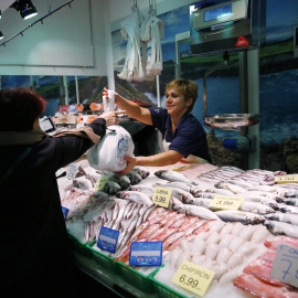 Una mujer haciendo la compra en una pescadería de un mercado de Madrid. REUTERS