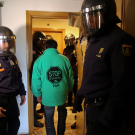 Un activista antidesahucios abandona entre agentes de la policía el domicilio de Jose Antonio Rojas Marcos y Jessica Guabala de la Cruz, en Parla. REUTERS/Andrea Comas