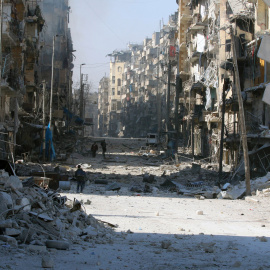 Varias personas andan por una calle del este de Alepo destrozada por los bombardeos. - REUTERS