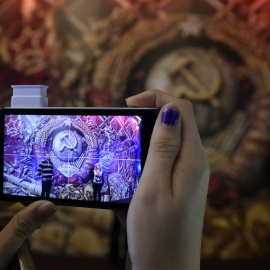 Una mujer toma una imagen de un emblema de la URSS durante una exposición en Moscú. - AFP