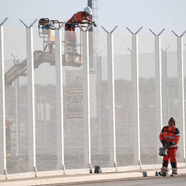 Operarios franceses colocan alambres de púas en una valla del puerto de Calais. /  REUTERS