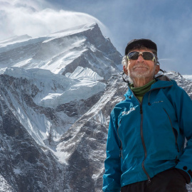 Carlos Soria con el Annapurna de fondo y los fuertes vientos en su cumbre.