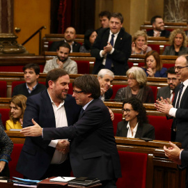 El presidente de la Generalitat, Carles Puigdemont, felicita al vicepresidente y conseller de Economía, Oriol Junqueras, al finalizar la votación en la que el Govern ha conseguido la admisión a trámite de la Ley de Presupuestos con el apoyo