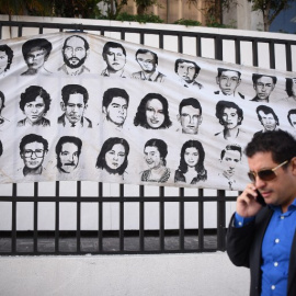 Un hombre pasa en Ciudad de Guatemala junto a un mural con rostros de desaparecidos durante el conflicto armado. - AFP