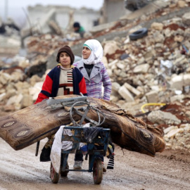 Samah, 11, y su hermano Ibrahim transportan sus pertenencias salvadas de su casa destrozada por la guerra en Alepo. / REUTERS