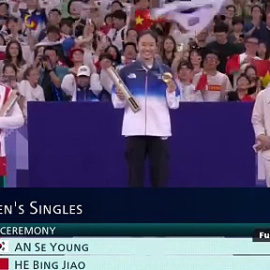 La deportista china He Bingjiao rinde homenaje a Carolina Marín en el podio tras la lesión de la española