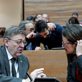 El presidente de la Generalitat valenciana, Ximo Puig, conversa con la vicepresidenta del Consell, Mónica Oltra, al comienzo del pleno que, entre otros puntos, debate y vota el proyecto de ley de la función social de la vivienda. EFE/Manuel