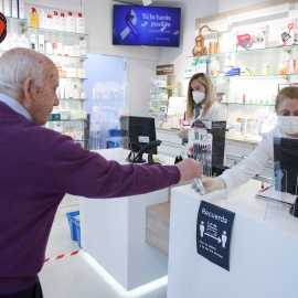 Un cliente mantiene la distancia de seguridad mientras es atendido en una farmacia del centro de Madrid. EFE/David Fernández