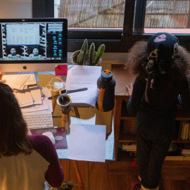 Una mujer trabaja desde casa mientras su hija juega a su lado. EFE