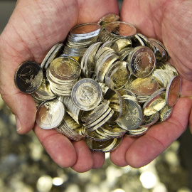 Un hombre recoge en sus manos monedas de euro. EFE