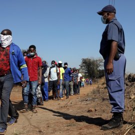  Una cola de personas con mascarillas para recibir ayuda alimentaria en el asentamiento informal de Itireleng, cerca del suburbio de Laudium en Pretoria, Sudáfrica. REUTERS / Siphiwe Sibeko