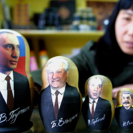 Una tendera china enseña una colección de muñecas matrioskas con las caras de Putin, Yeltsin, Gorbachov, Stalin y Lenin.- AFP