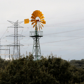 Un molino de viento cerca de unas torres eléctricas de alta tensión en la localidad madrileña de Galapagar. REUTERS