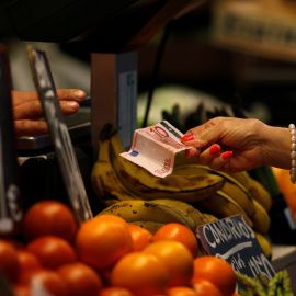 Una mujer paga después de hacer la compra en un puesto de frutas y verduras en un mercado en Málaga. REUTERS/Jon Nazca
