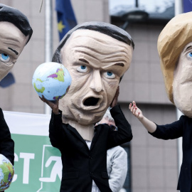  Activistas ambientales con máscaras que imitan a los líderes de la UE, el primer ministro de los Países Bajos, Mark Rutte (izquierda), el presidente de Francia, Emmanuel Macron (centro) y la canciller de Alemania, Angela Merkel (derecha), 
