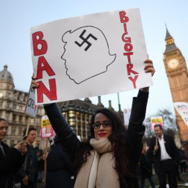 Una manifestante sujeta una pancarta en contra de las políticas antiinmigración de Trump. - AFP