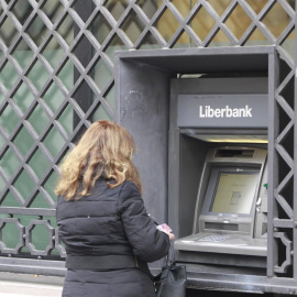 Una mujer opera un cajero automático en una oficina de Liberbank. E.P.