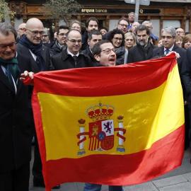 Un hombre despliega una bandera española ante la presencia de Francesc Homs y de Artur Mas en el paseo hacia el Tribunal Supremo. /EFE