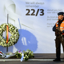 Un policía monta guardia junto a un mural en memoria de las víctimas de los atentados del 22 de marzo de 2016. - AFP