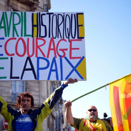 Un hombre sostiene una pancarta con la frase, en francés, "8 de abril histórico. El valor de la paz", junto a otro hombre con las banderas vasca y catalana, en baiona. REUTERS / Vincent West