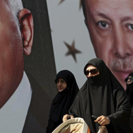 Varios ciudadanos pasan delante de un cartel gigante del presidente turco, Recep Tayyip Erdogan, en Estambul. | SEDAT SUNA (EFE)