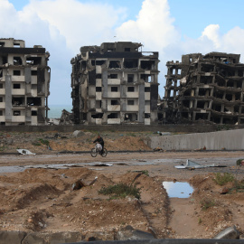 Un gazatí pasa en bici por delante de tres edificios destruidos en Ciudad de Gaza. EFE/ Str