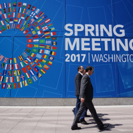 Unos peatones pasan por delante del mural que anuncia la reunión de primavera del FMI y del Banco Mundial en Washington. AFP/Mandel Ngan