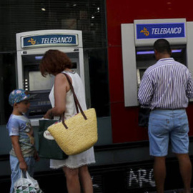Un par de personas utilizan los cajeros de un banco en Madrid. EFE