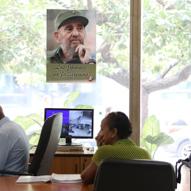 Trabajadores del centro internacional de prensa ante una fotografía de Fidel. /Marian León y Lucía M. Quiroga