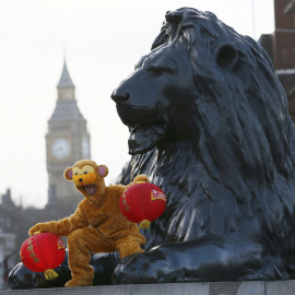 Un hombre disfrazado de mono posa desde uno de los leones de Trafalgar Square para dar la bienvenida al Año Nuevo del Mono de Fuego Chino, en Londres, Inglaterra. REUTERS/Stefan Wermuth