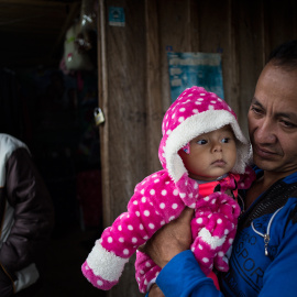 Un guerrillero sostiene en brazo a su hija de pocos meses en el campamento para desmovilizados de las FARC en La Fila, región de Tolima.-JAIRO VARGAS