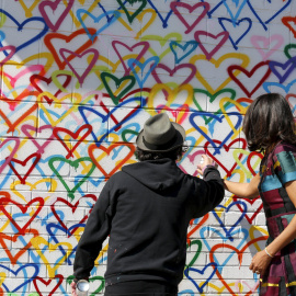 La primera dama Michelle Obama de EEUU y el artista Mr. Brainwash añaden pintura en aerosol en un mural durante una visita a Union Market, en un evento para celebrar el Día Internacional de la Mujer en Washington. REUTERS/Kevin Lamarque