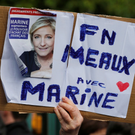 Un seguidor del Frente Nacional, sujeta una pancarta con la imagen de Marine Le Pen. REUTERS/Pascal Rossignol